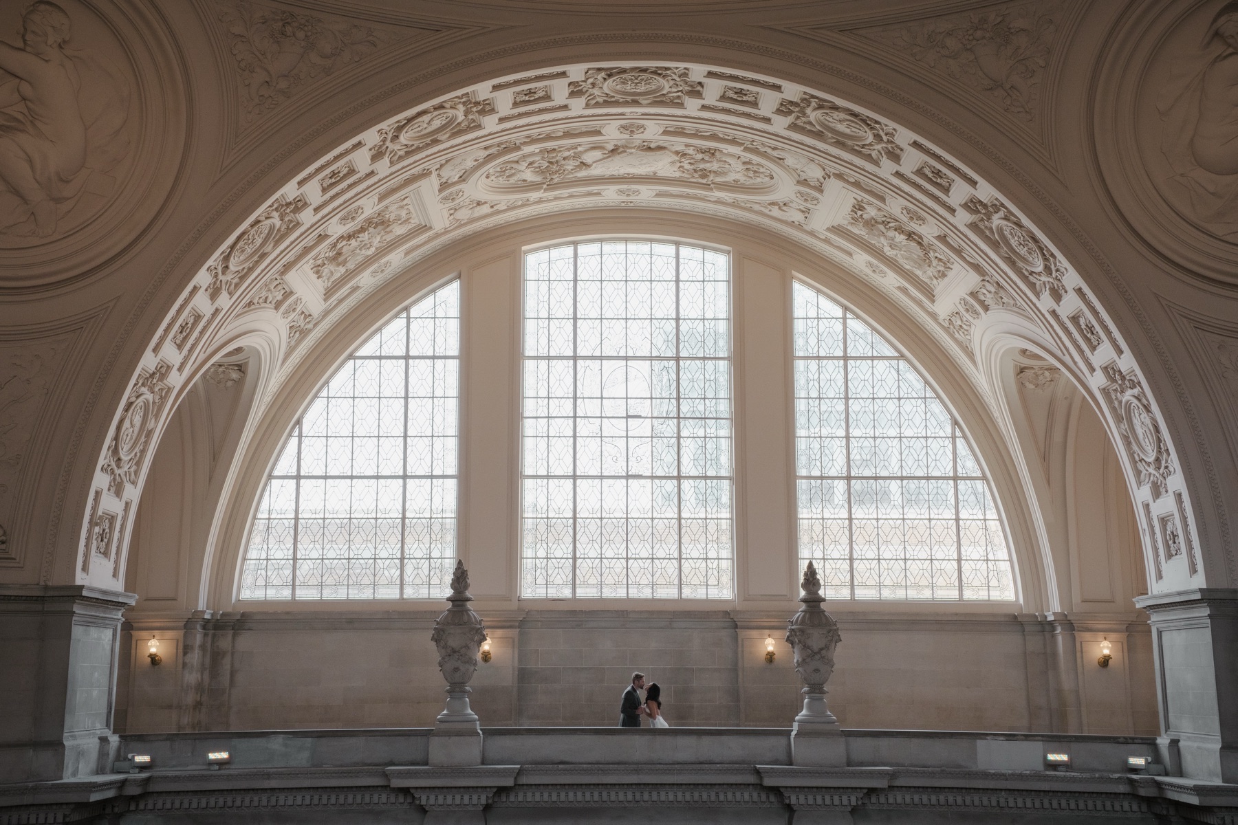 Silhouette of couple dancing against arch windows in the 4th floor rotunda at San Francisco City Hall
