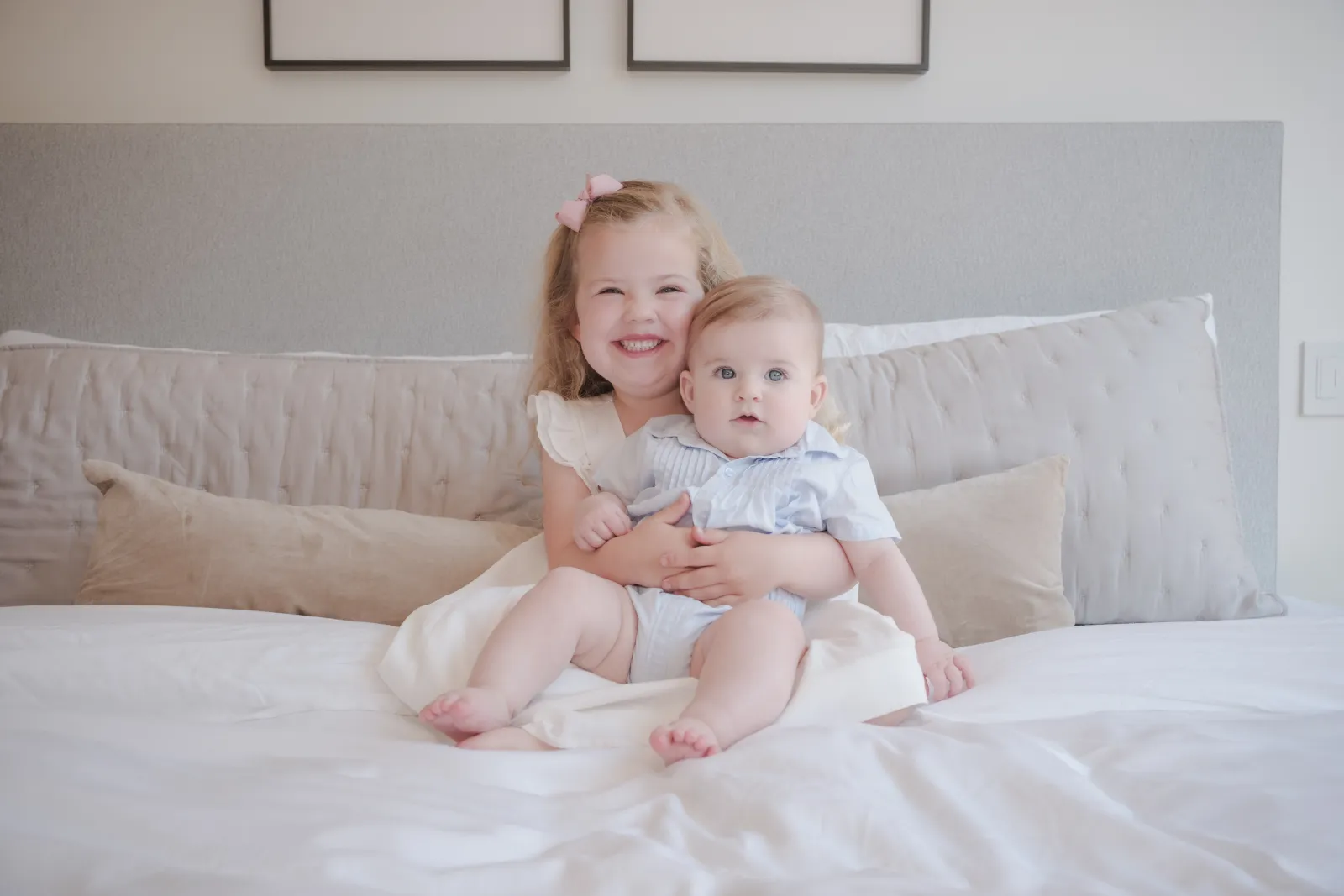 Smiling four-year-old girl hugging her baby brother on her parents' bed
