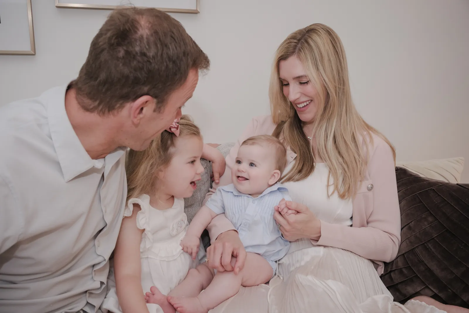 Parents smiling at their young daughter and baby son on the living room sofa