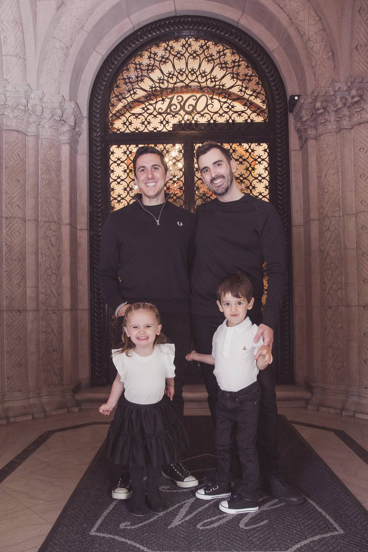 Family of four standing in the arched entryway of their Nob Hill apartment building