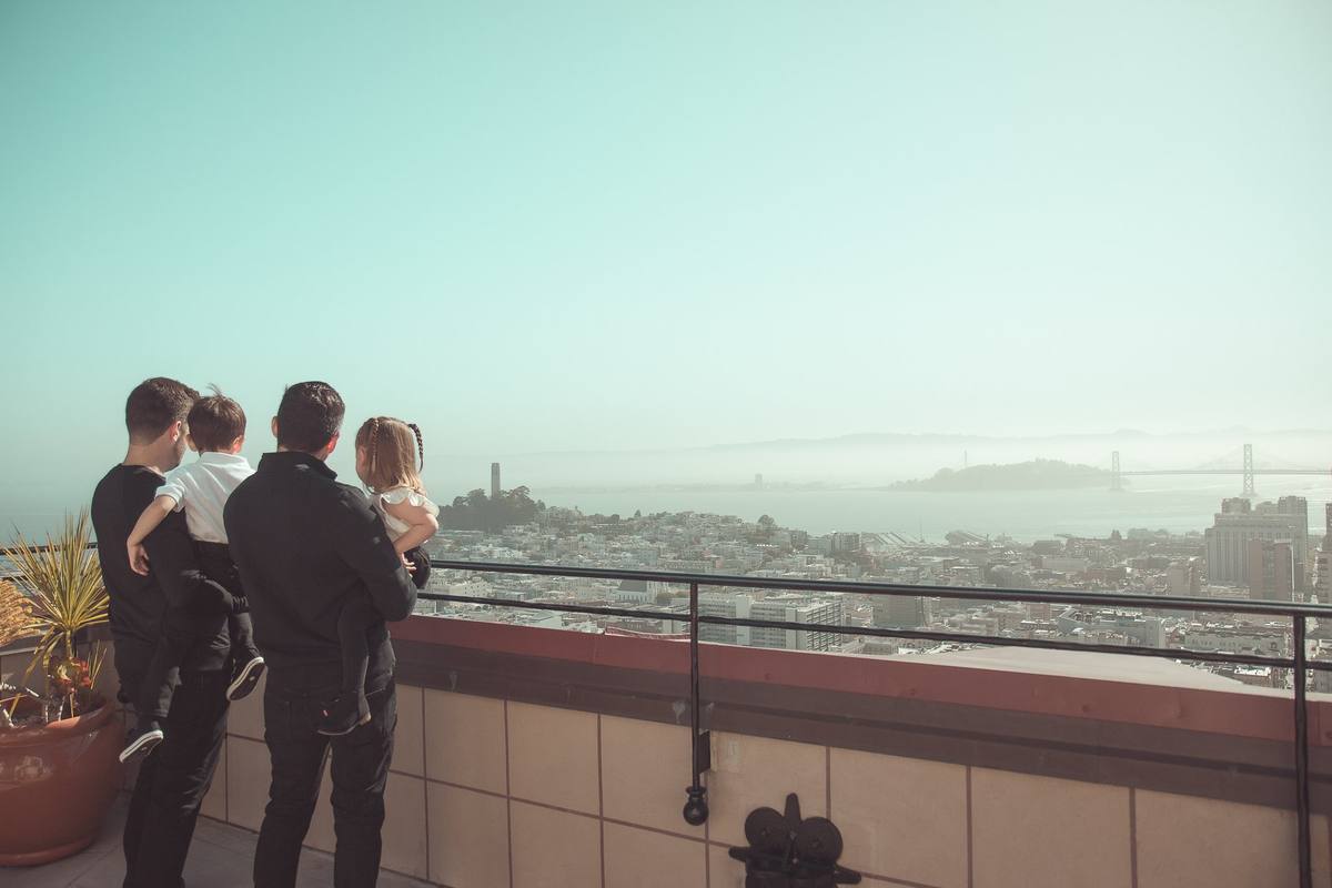 Family looking out over North Beach, Coit Tower, and the bay from their rooftop