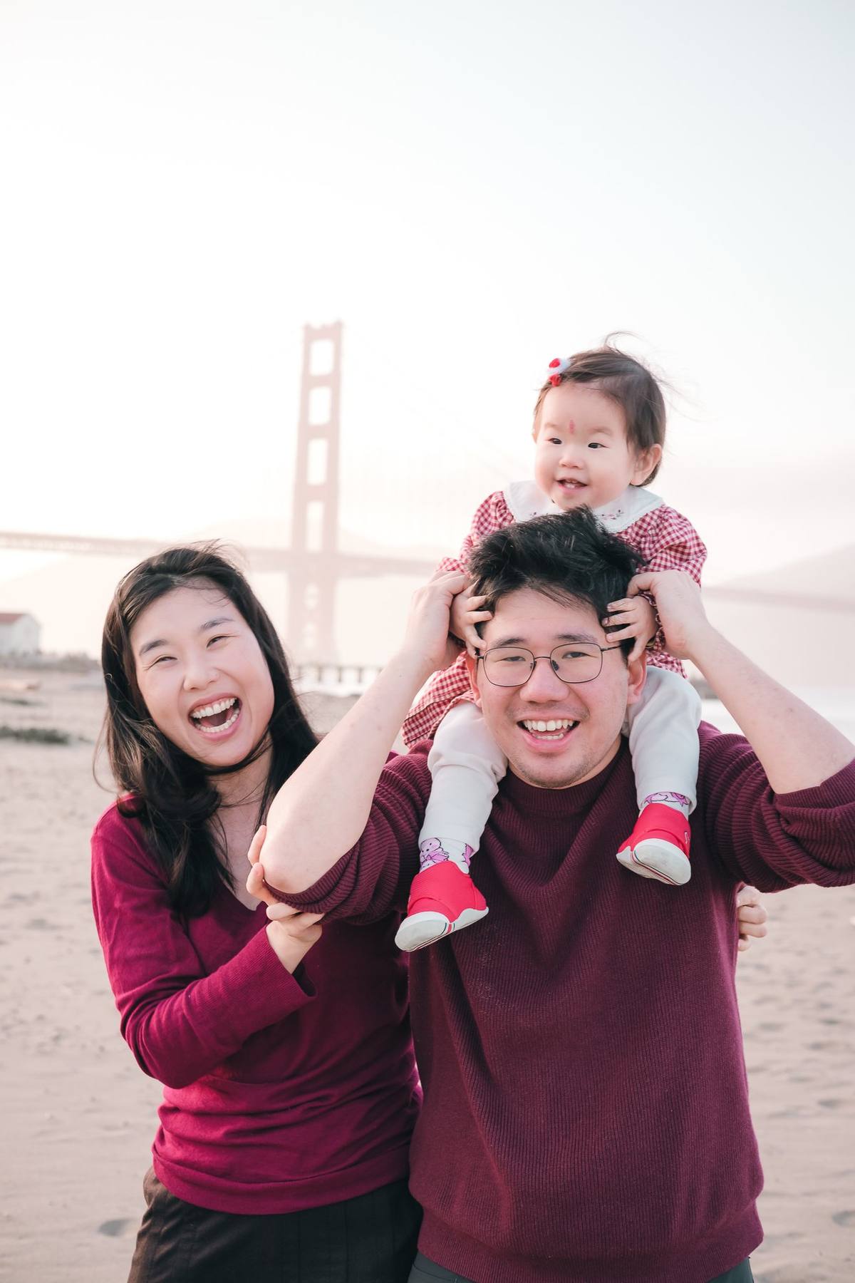 Baby girl riding on her father's shoulders while mom laughs beside them at Crissy Field