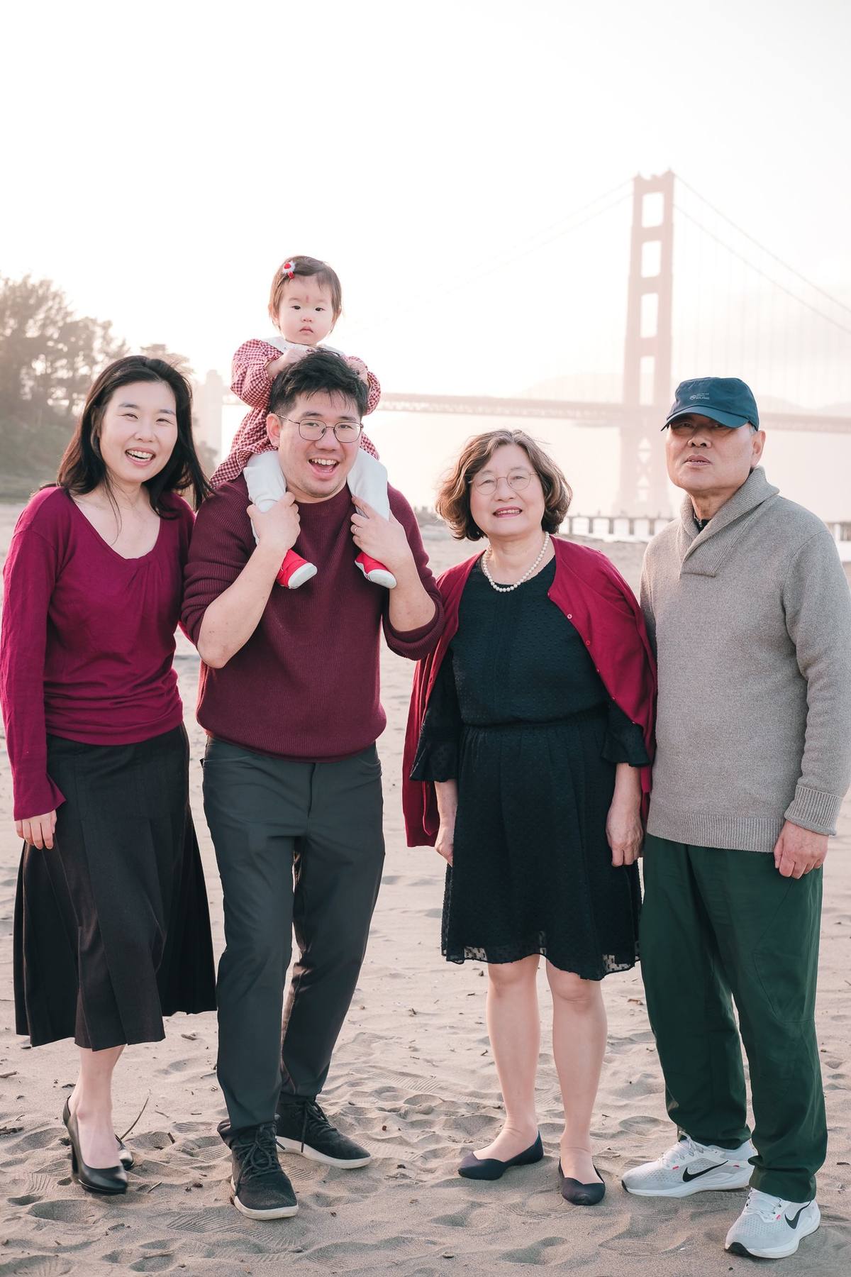 Three generations of a family together on the beach at Crissy Field with the Golden Gate Bridge behind them