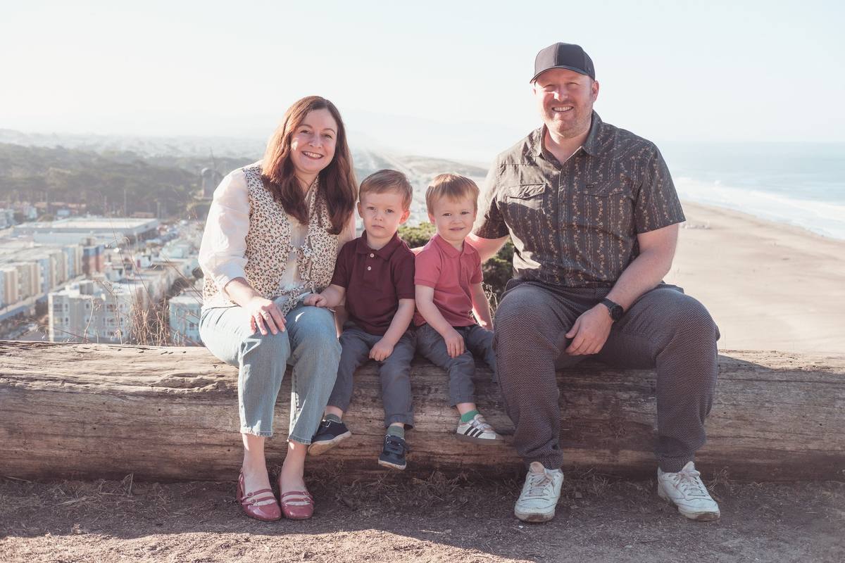 Parents and their two little boys sitting on a log above Ocean Beach at Sutro Park