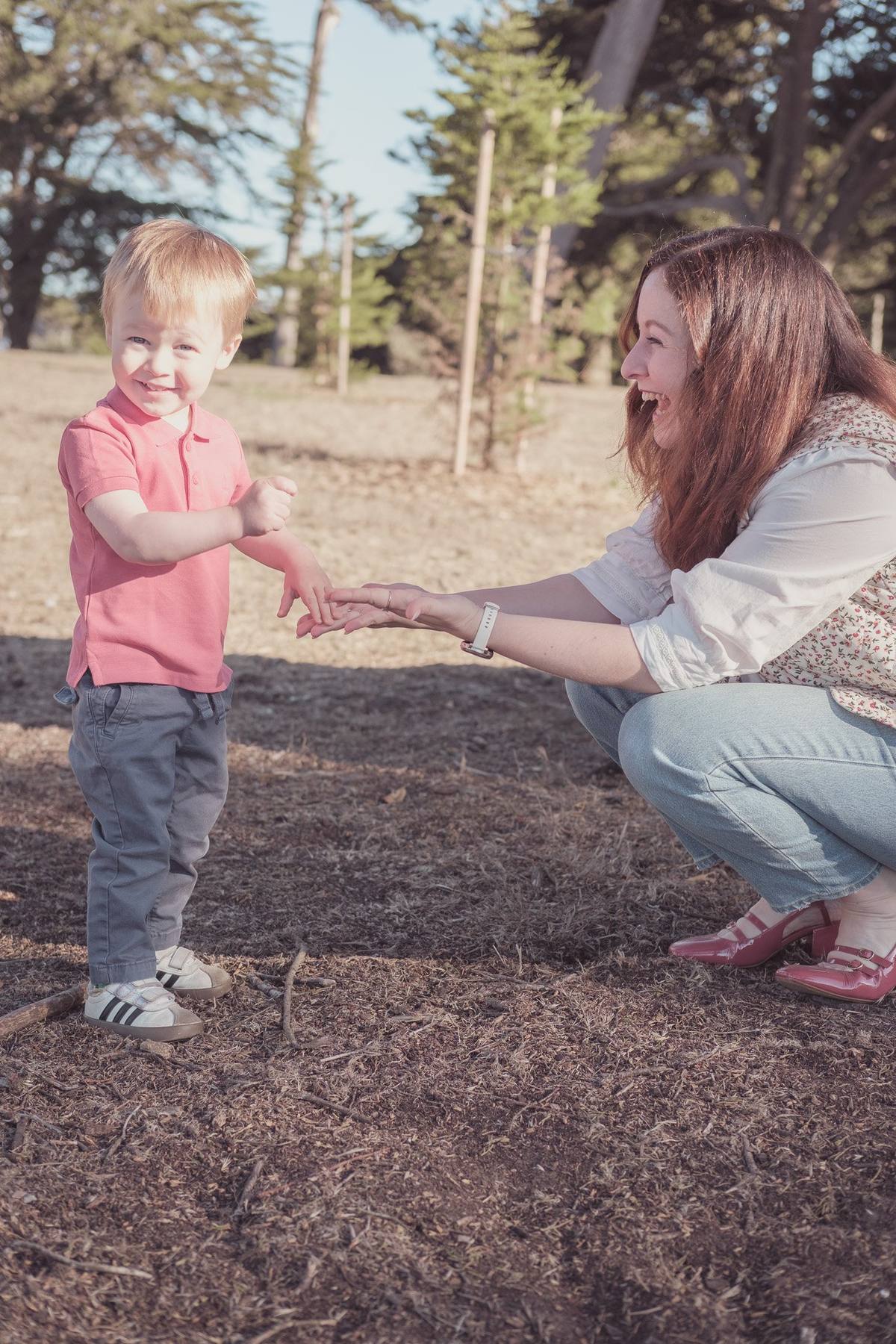 Mother crouching to hold hands with her toddler son at Sutro Park