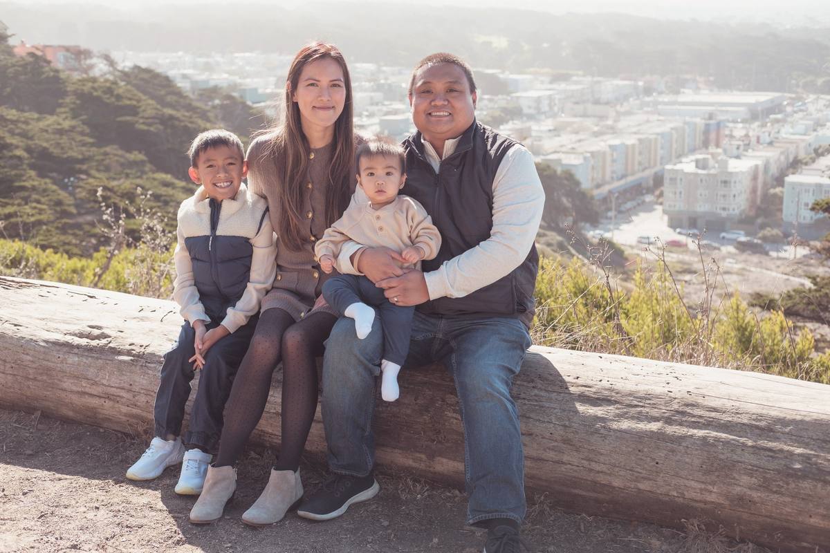 Family of four sitting on a log with the Richmond District behind them