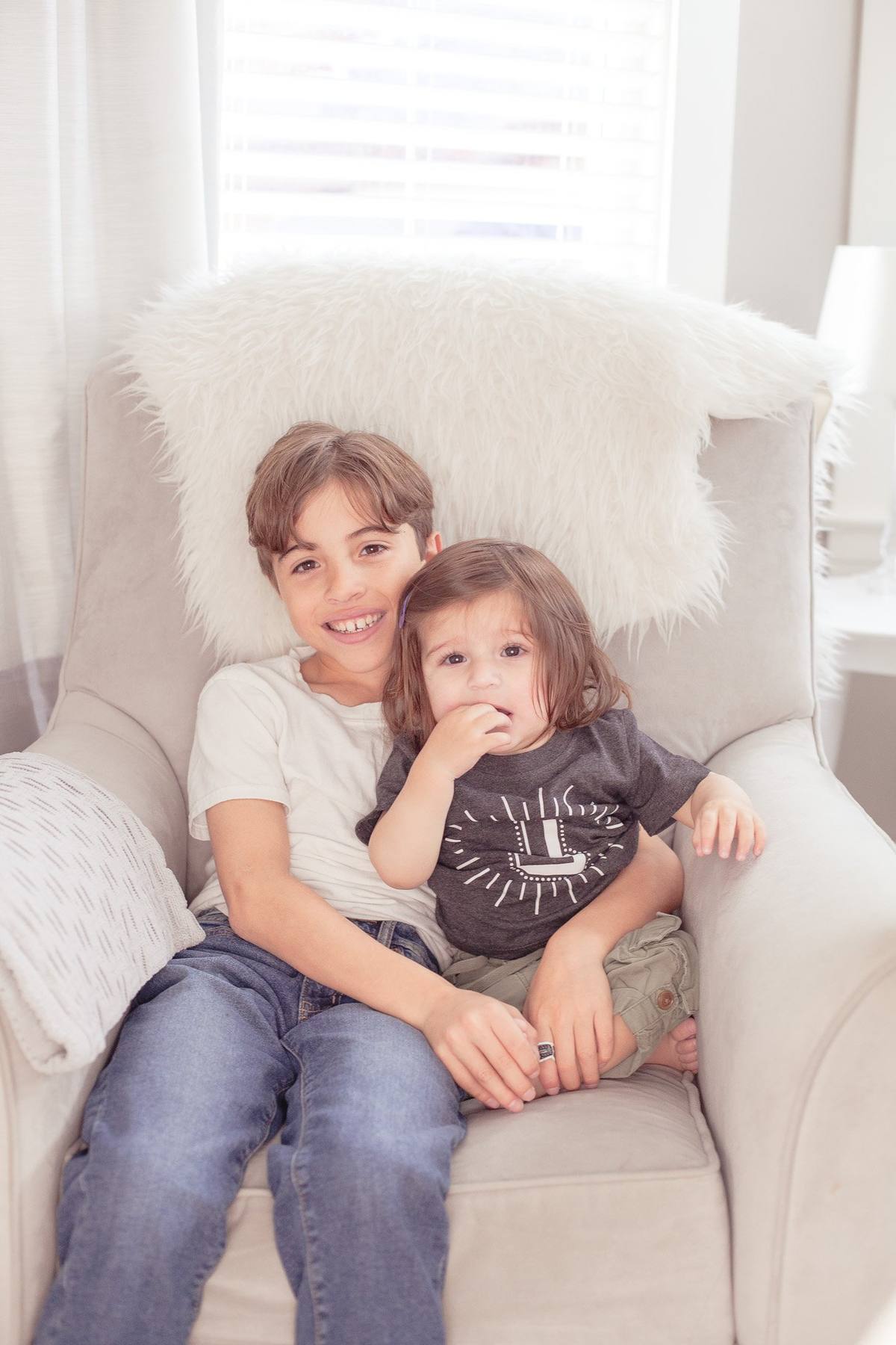 Two young brothers cuddled up together in an armchair in their living room