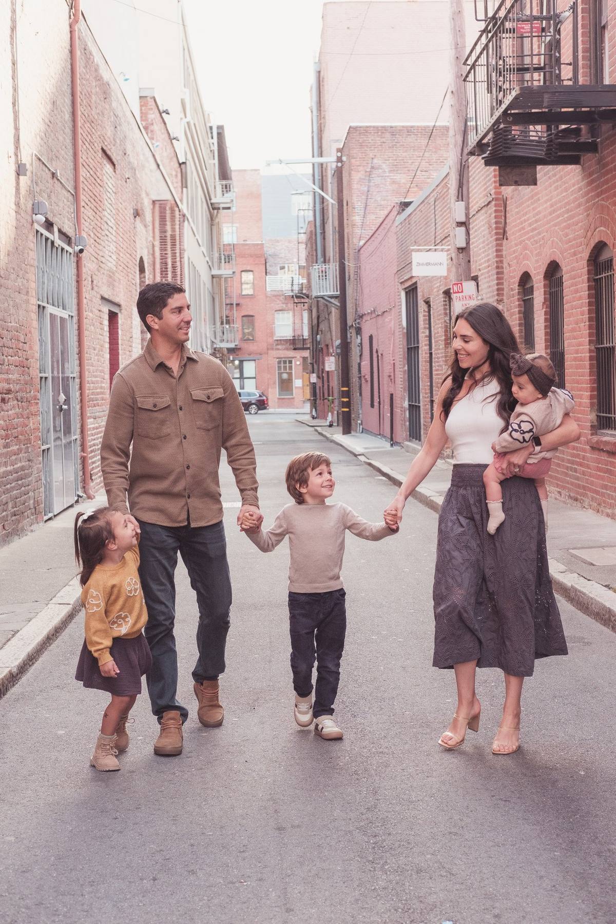 Family of five walking hand in hand down a brick-lined alley in Jackson Square