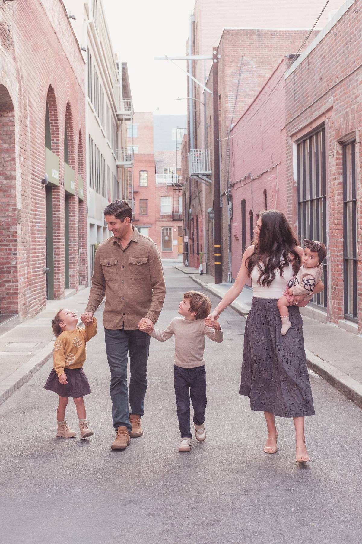 Parents and their two older children swinging hands as they walk down a Jackson Square alley
