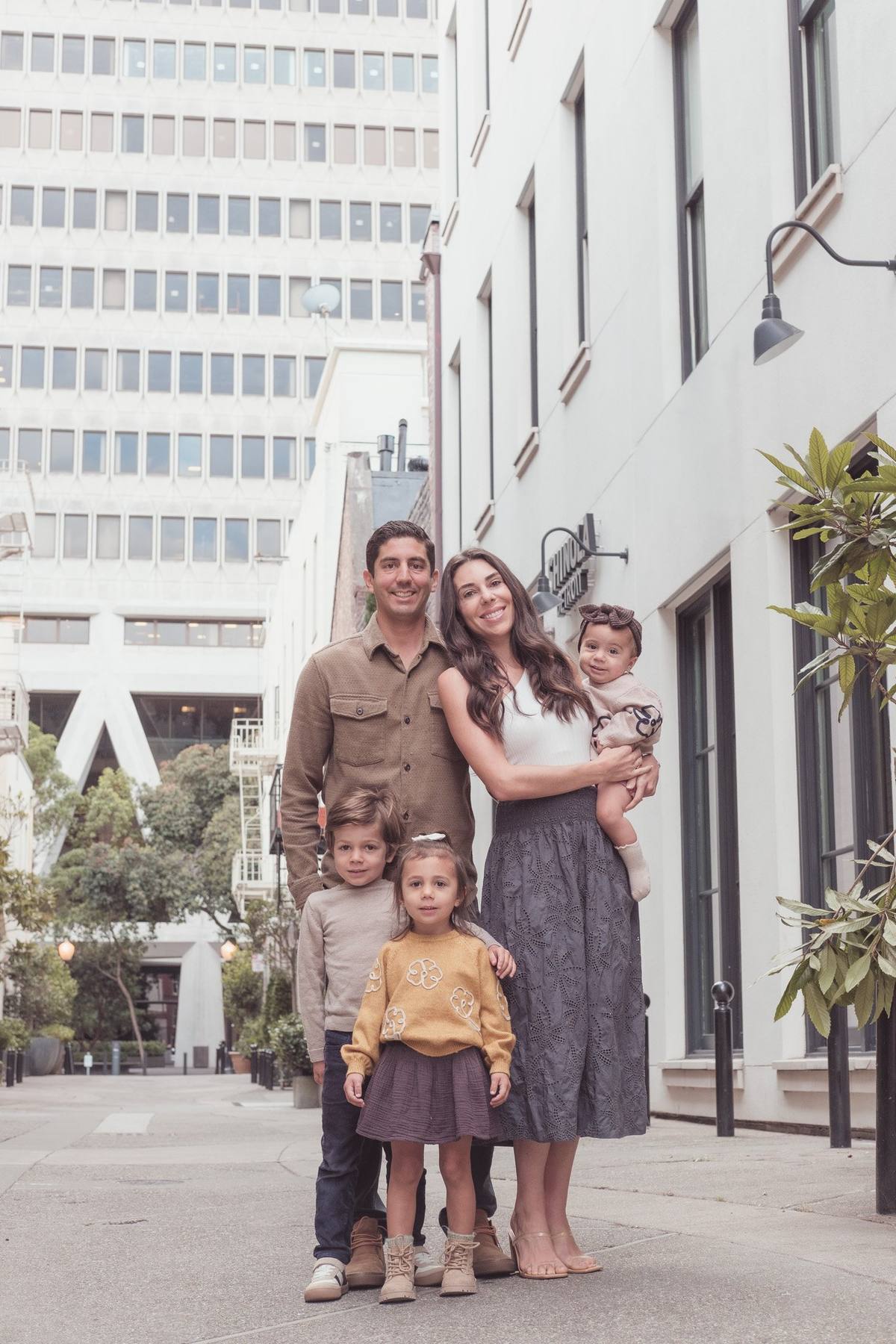 Family of five in an alley with the base of the Transamerica Pyramid behind them