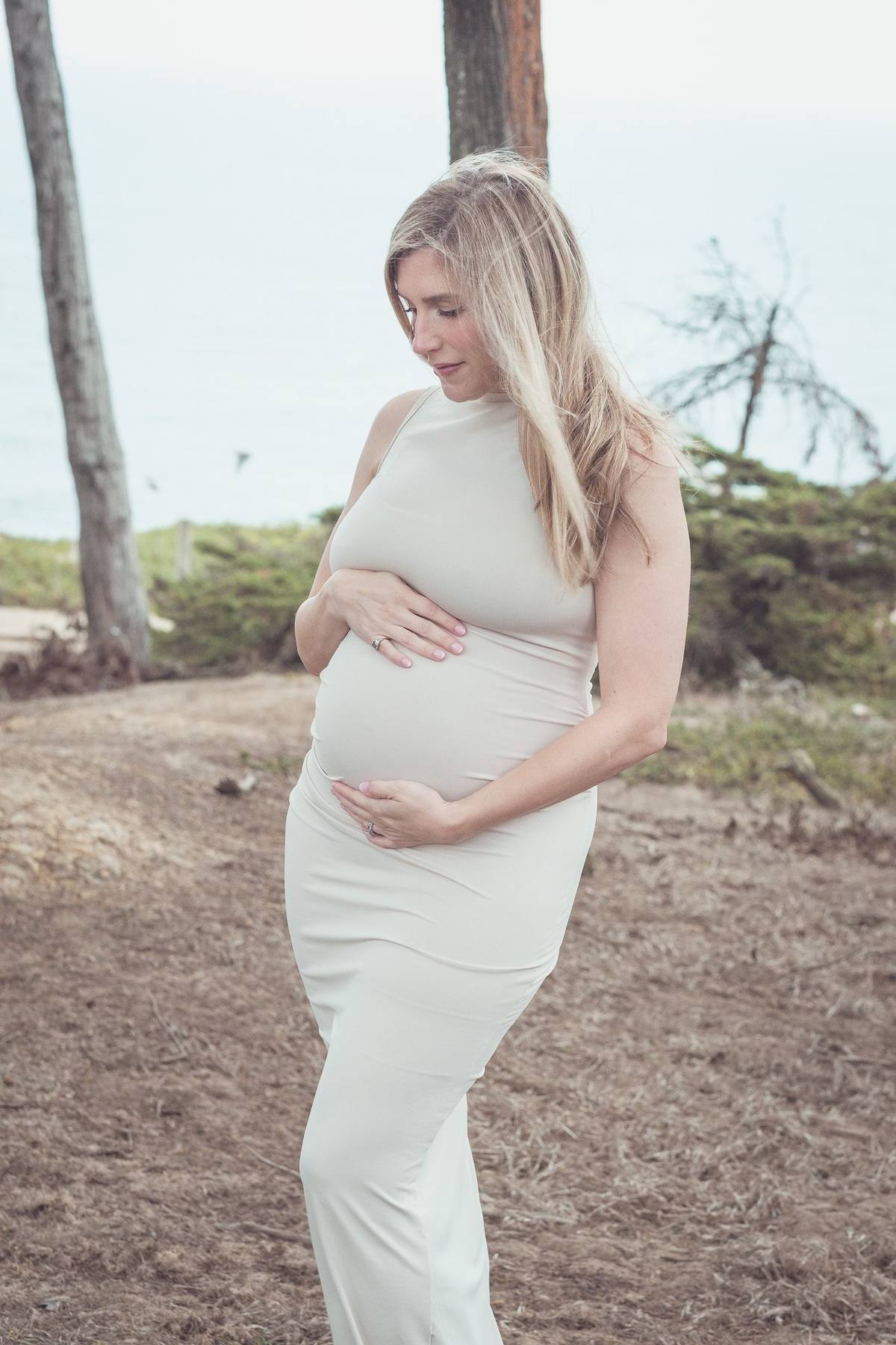 Pregnant mother gazing down at her bump on the trail at Lands End