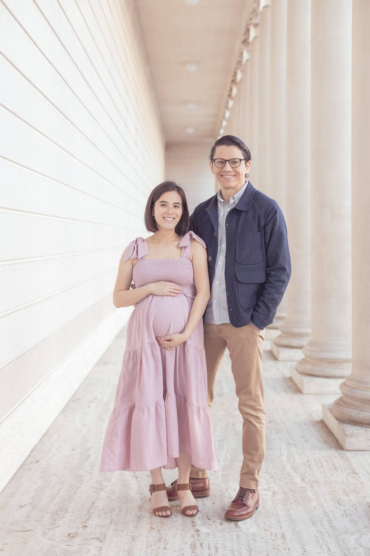 Expecting couple standing among the columns of the Legion of Honor colonnade
