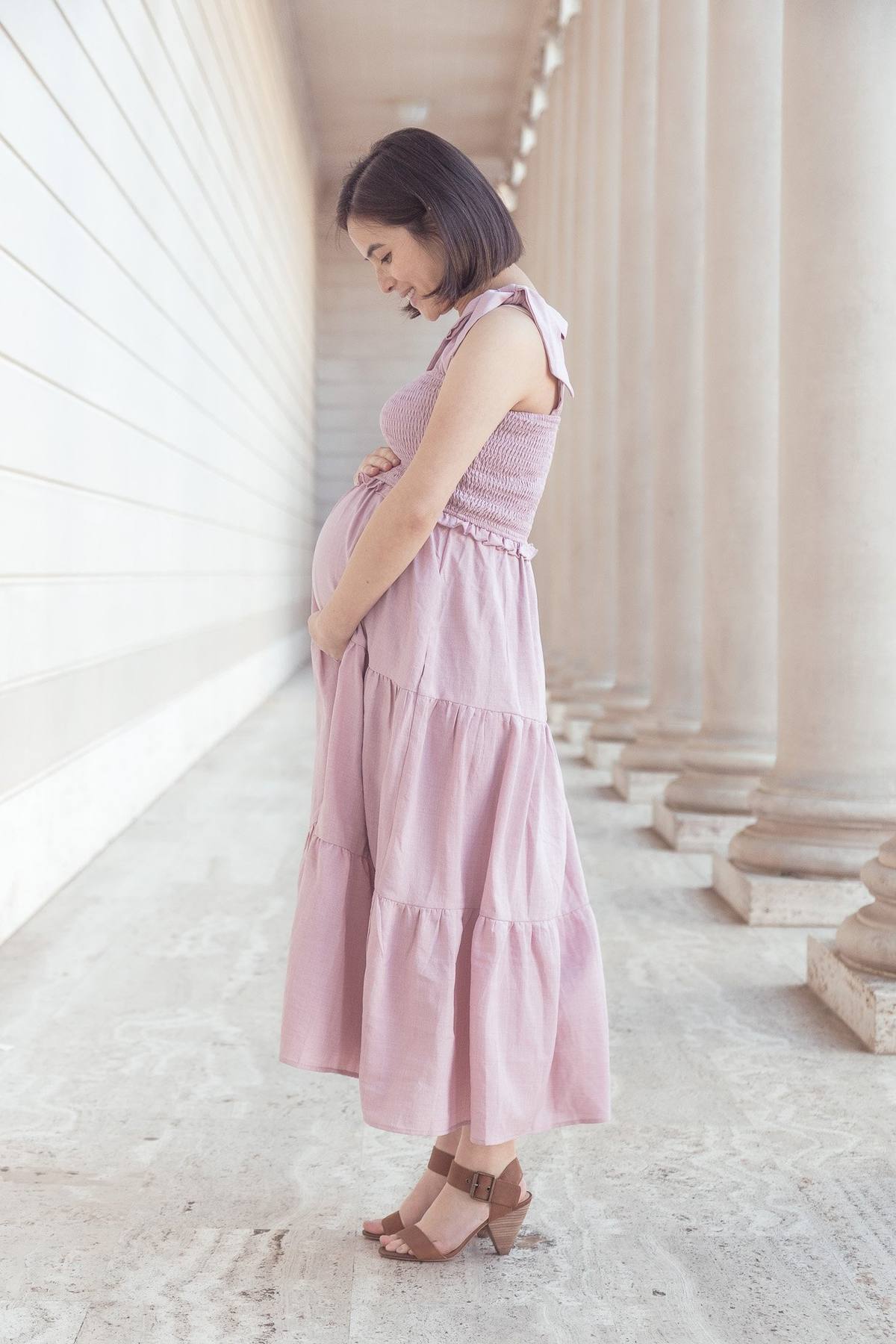 Pregnant woman looking down at her bump beneath the Legion of Honor colonnade