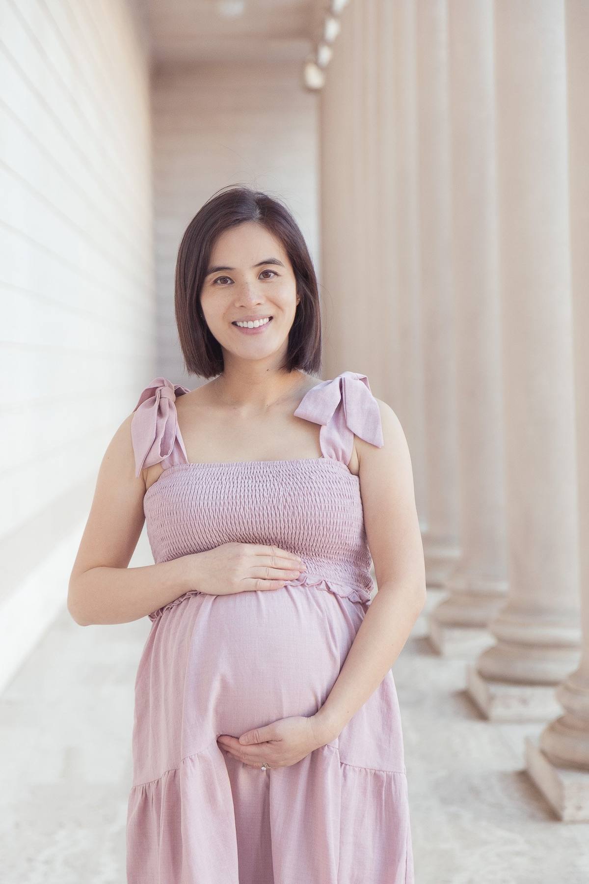 Pregnant woman smiling in the morning light of the Legion of Honor colonnade