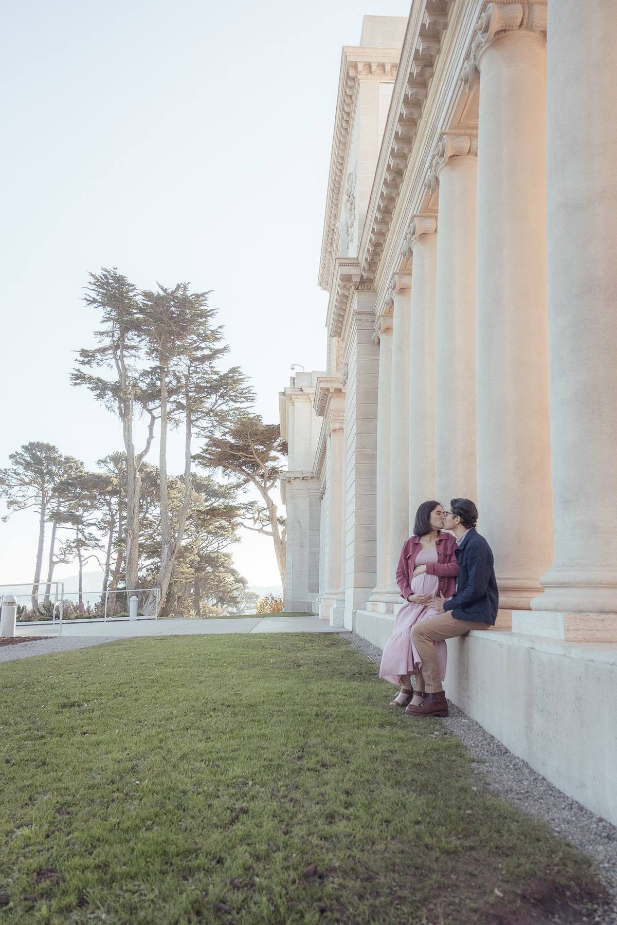 Couple sharing a kiss on a ledge beside the columns of the Legion of Honor
