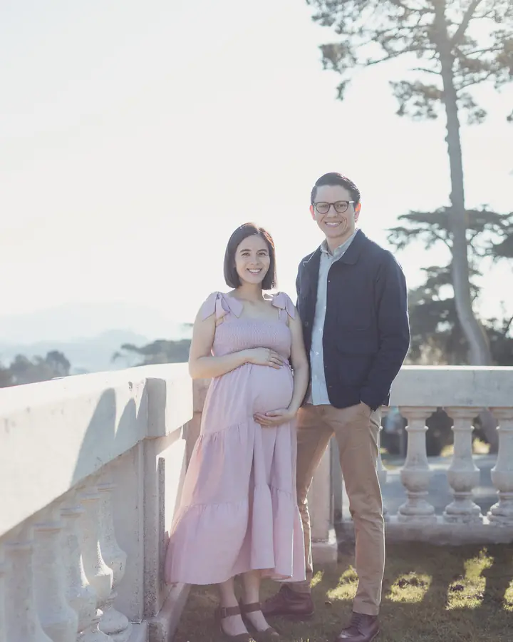 Expecting couple standing beside the stone balustrade at the Legion of Honor