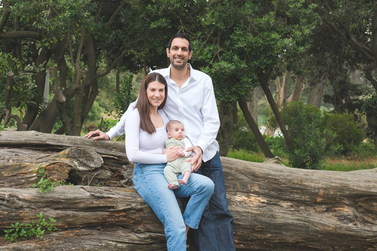 New parents sitting on a fallen log with their 10-week-old son in Golden Gate Park