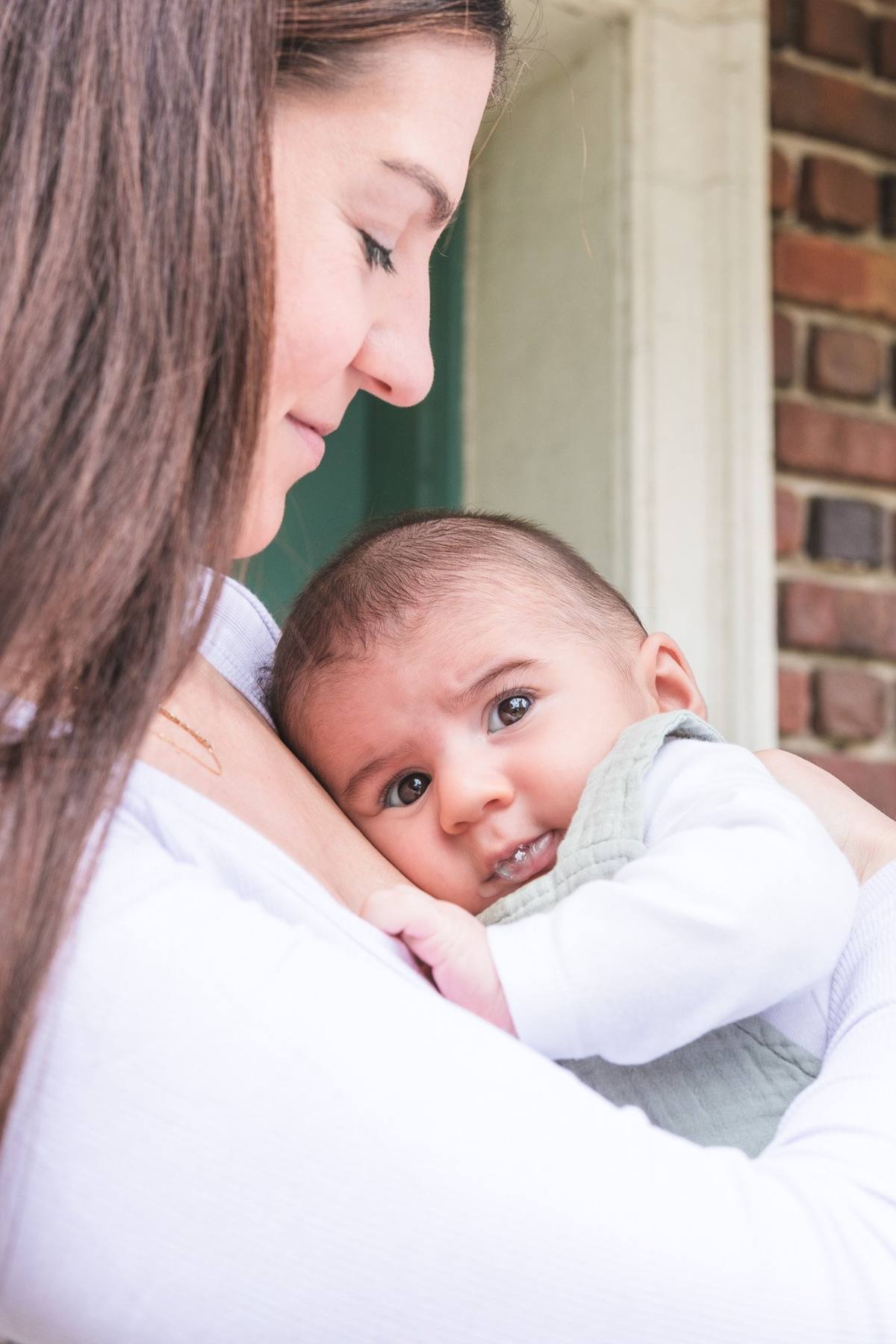 Baby boy resting his cheek on his mother's shoulder beside the Murphy Windmill