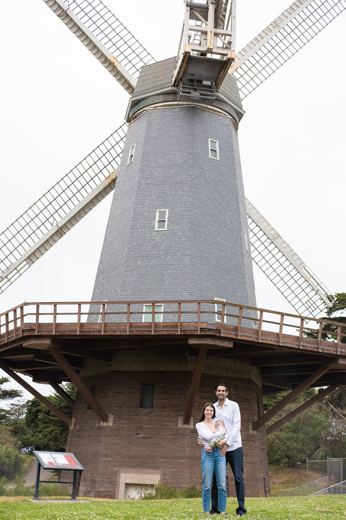 Family of three standing at the base of the Murphy Windmill in Golden Gate Park