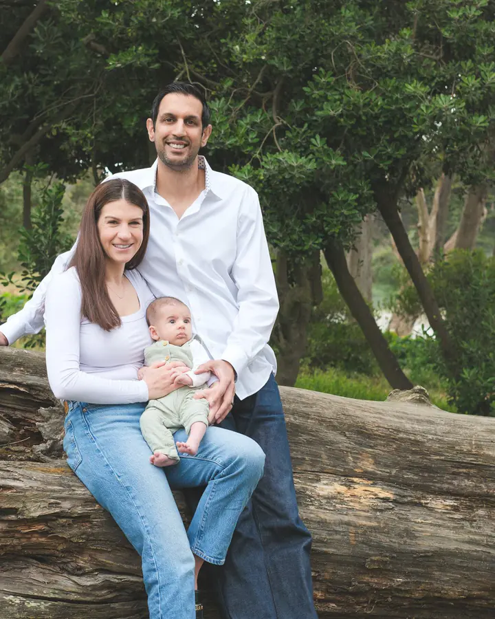 New parents sitting on a fallen log with their 10-week-old son in Golden Gate Park