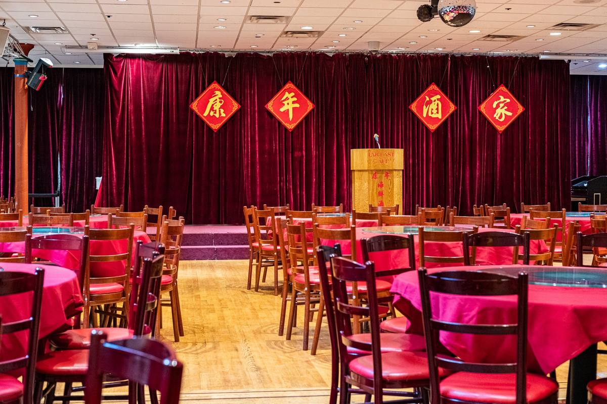 Banquet hall at the Far East Cafe with red velvet curtains and round tables set for the party