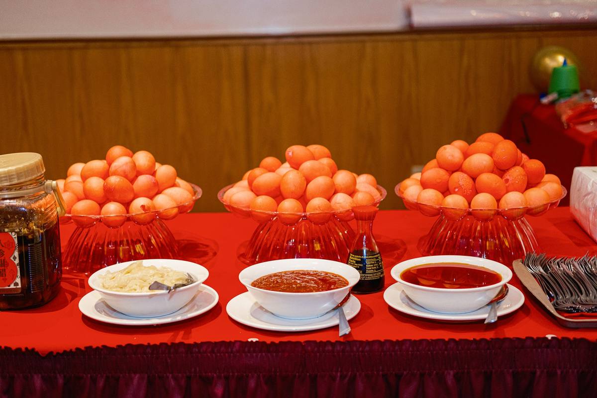 Bowls of red eggs and pickled ginger arranged on a red tablecloth