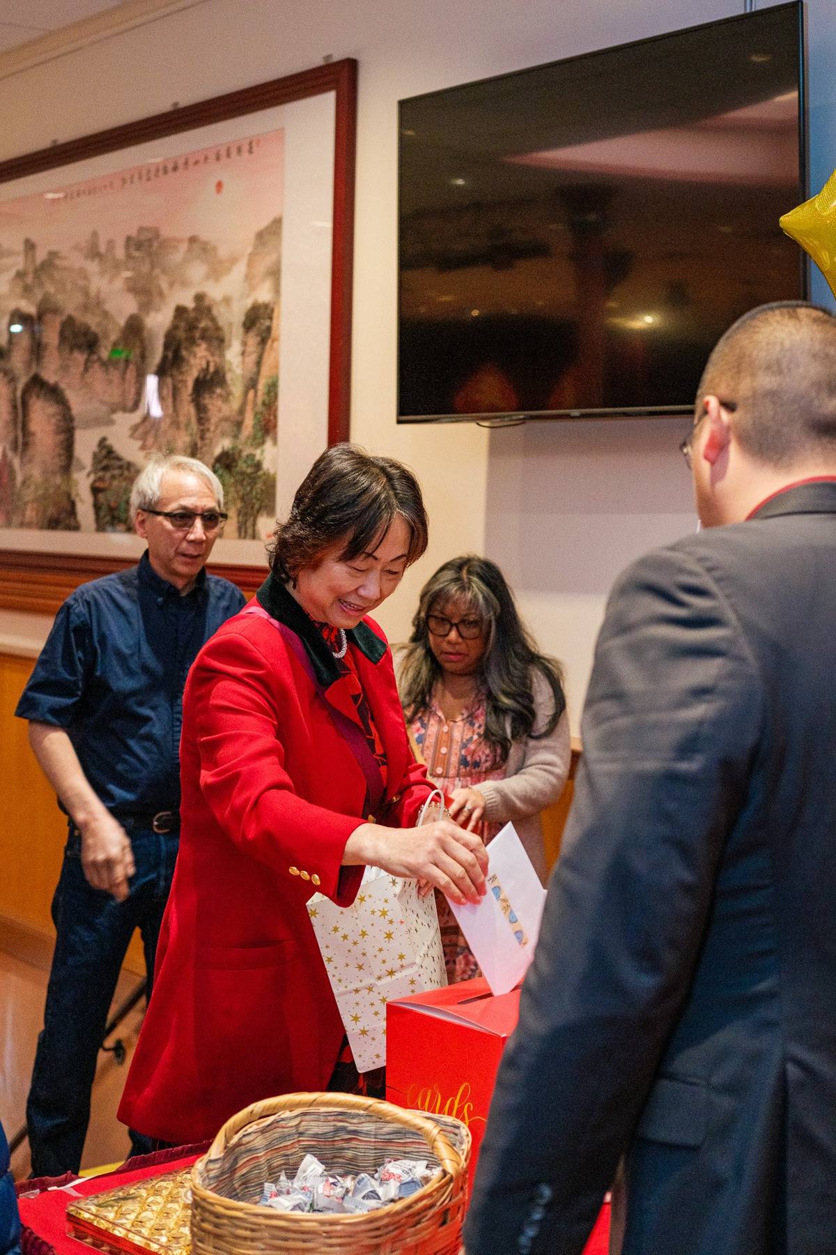 Guests dropping red envelopes into the gift box at the party