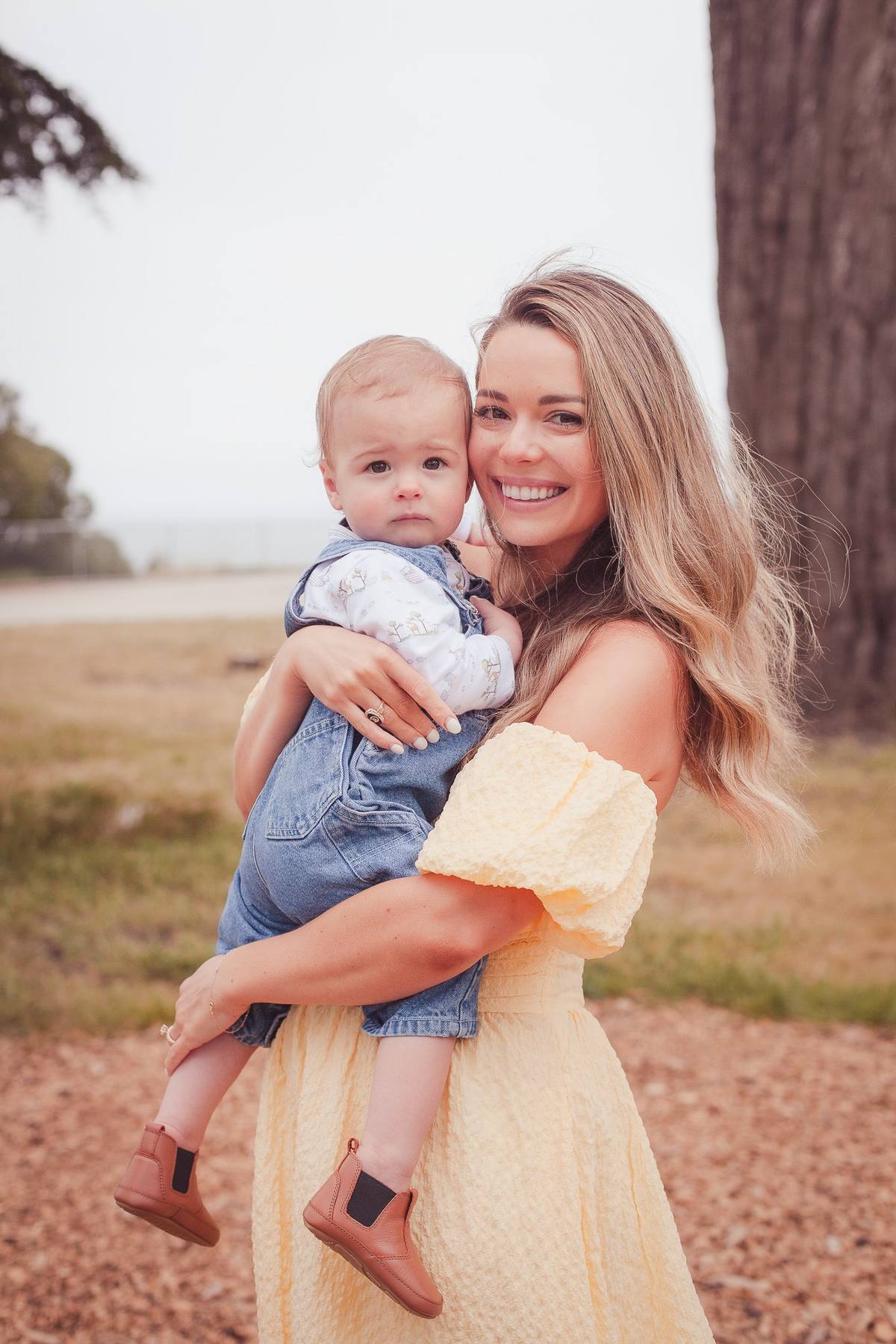 Mother holding her baby son on her hip under the trees at Sutro Park