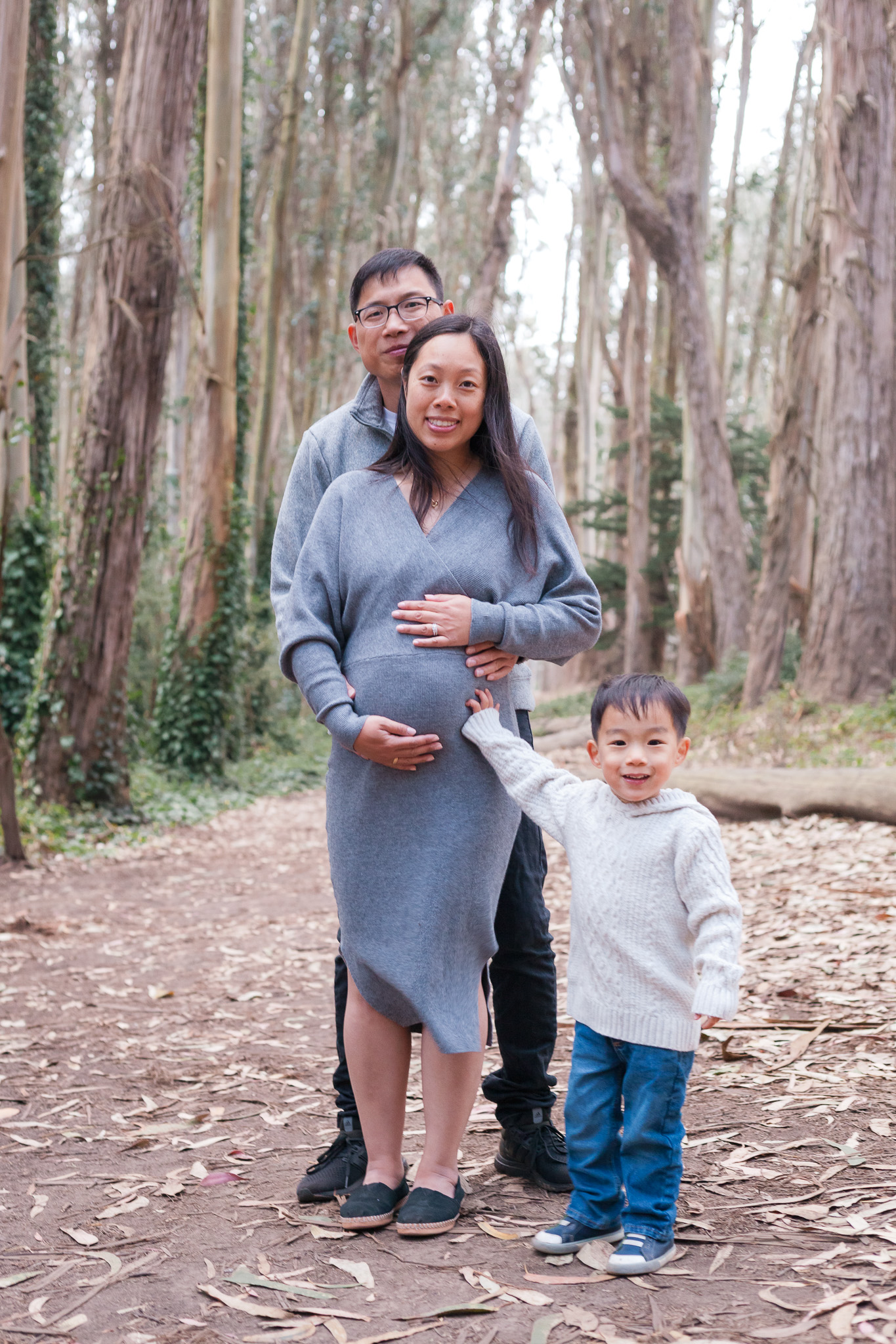 Expecting parents with their toddler son in a eucalyptus grove