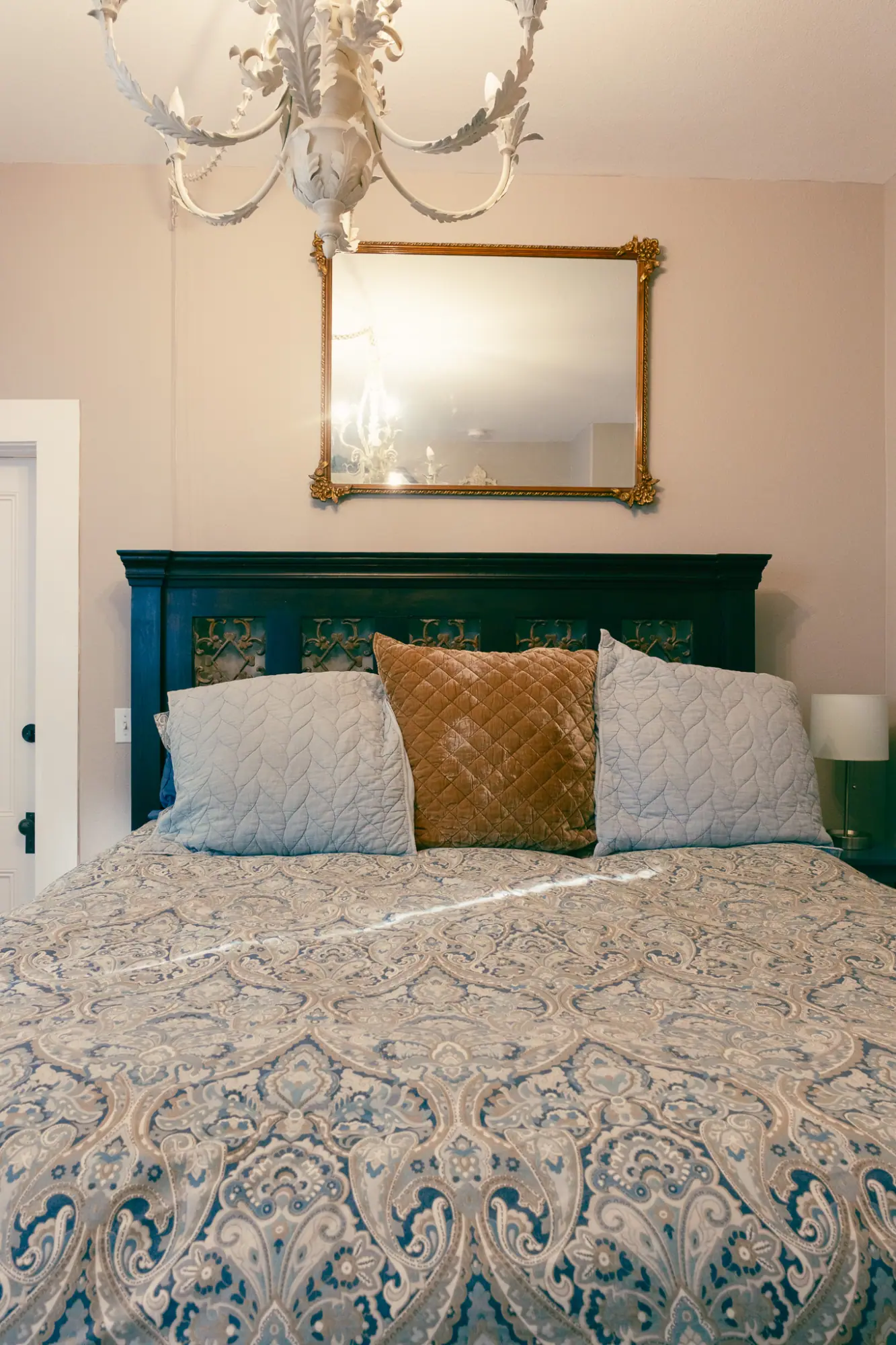 Bed with a gilt mirror and chandelier above it