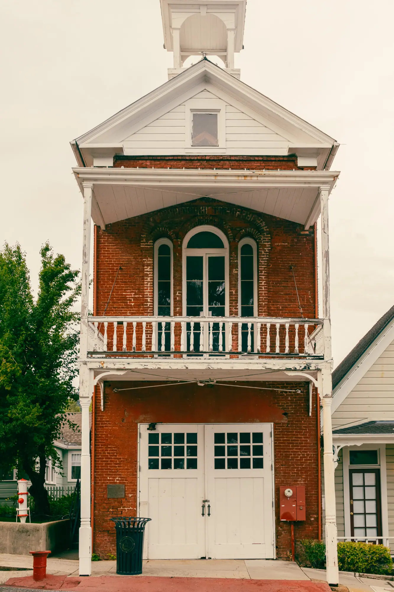 A brick firehouse with a white bell tower