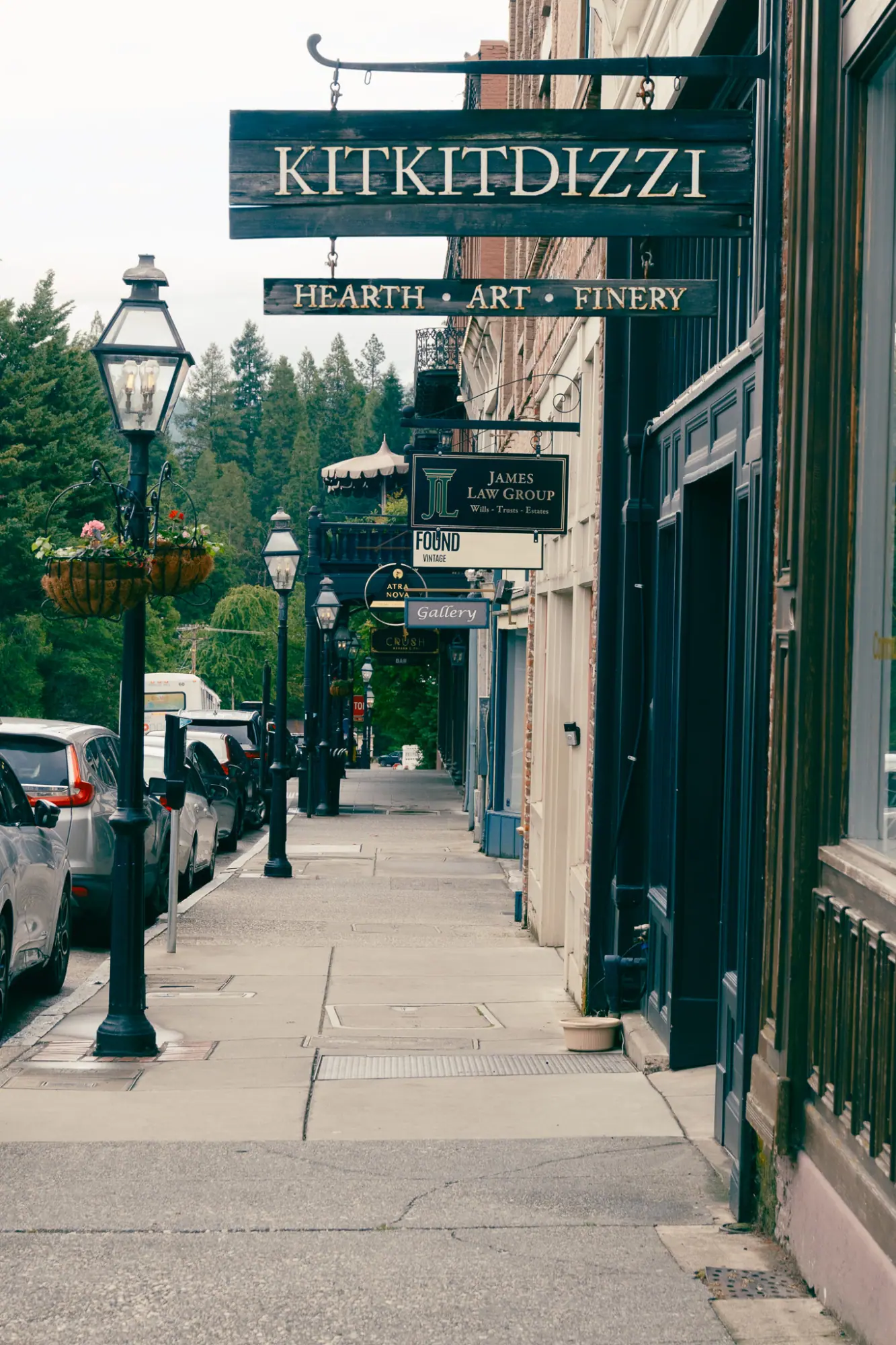 A sidewalk lined with lamp posts and hanging signs