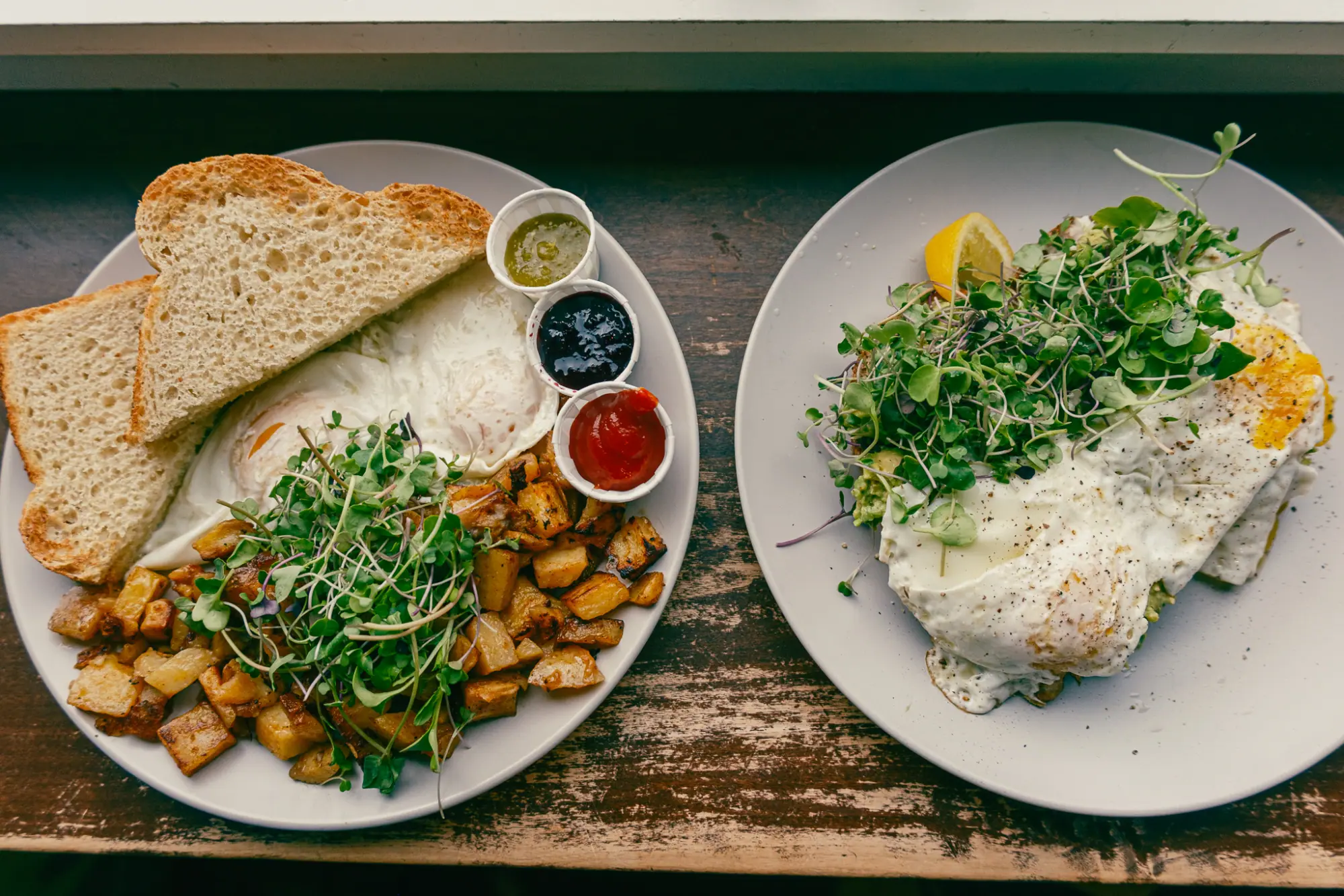 Two breakfast plates with toast, potatoes and eggs
