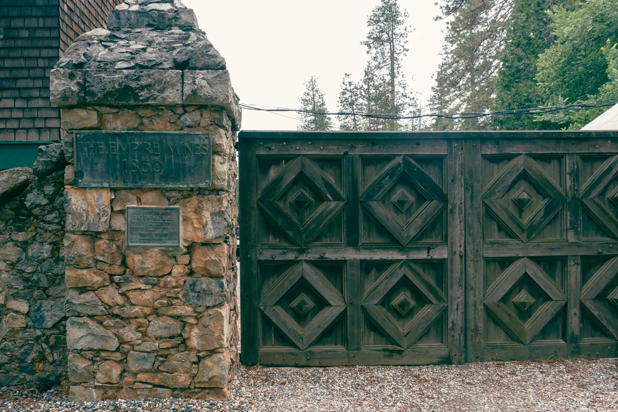 A stone gatepost and carved wooden gate