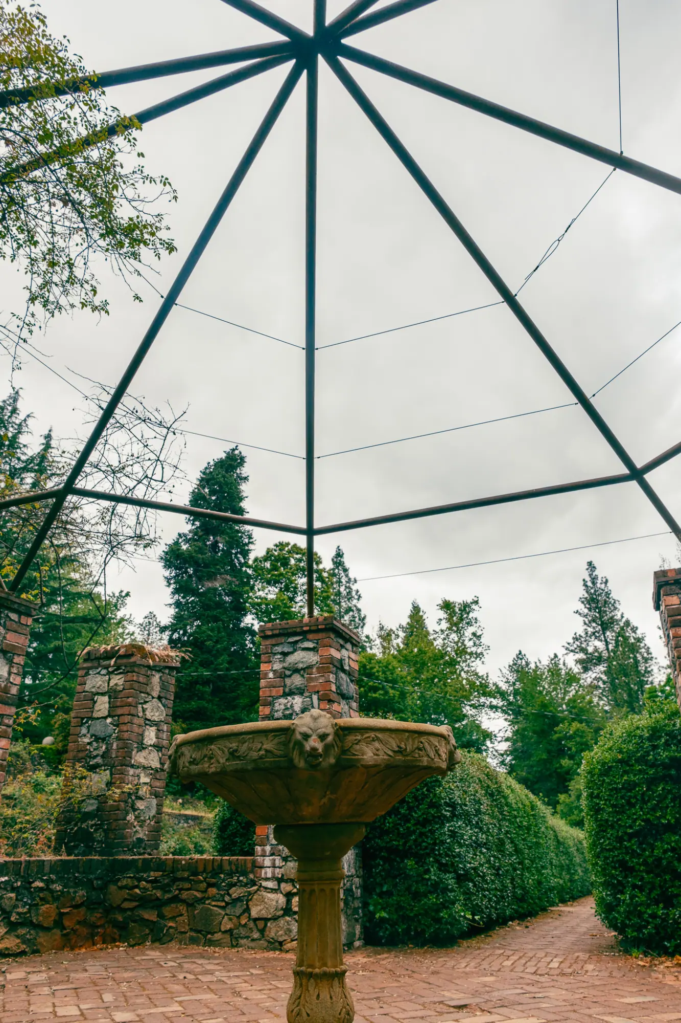 A fountain under a glass-and-iron pavilion frame