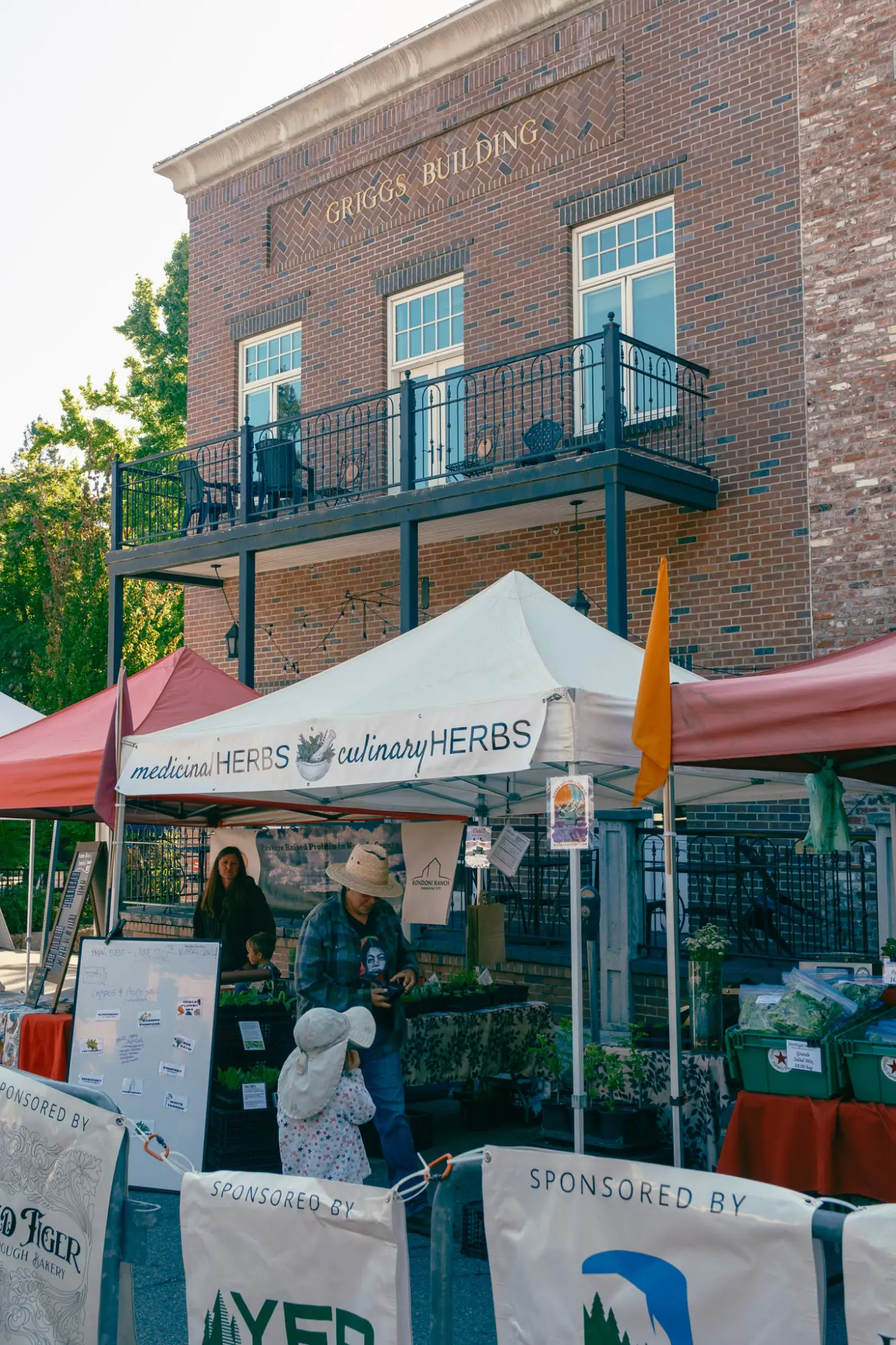 Market tents in front of a brick building