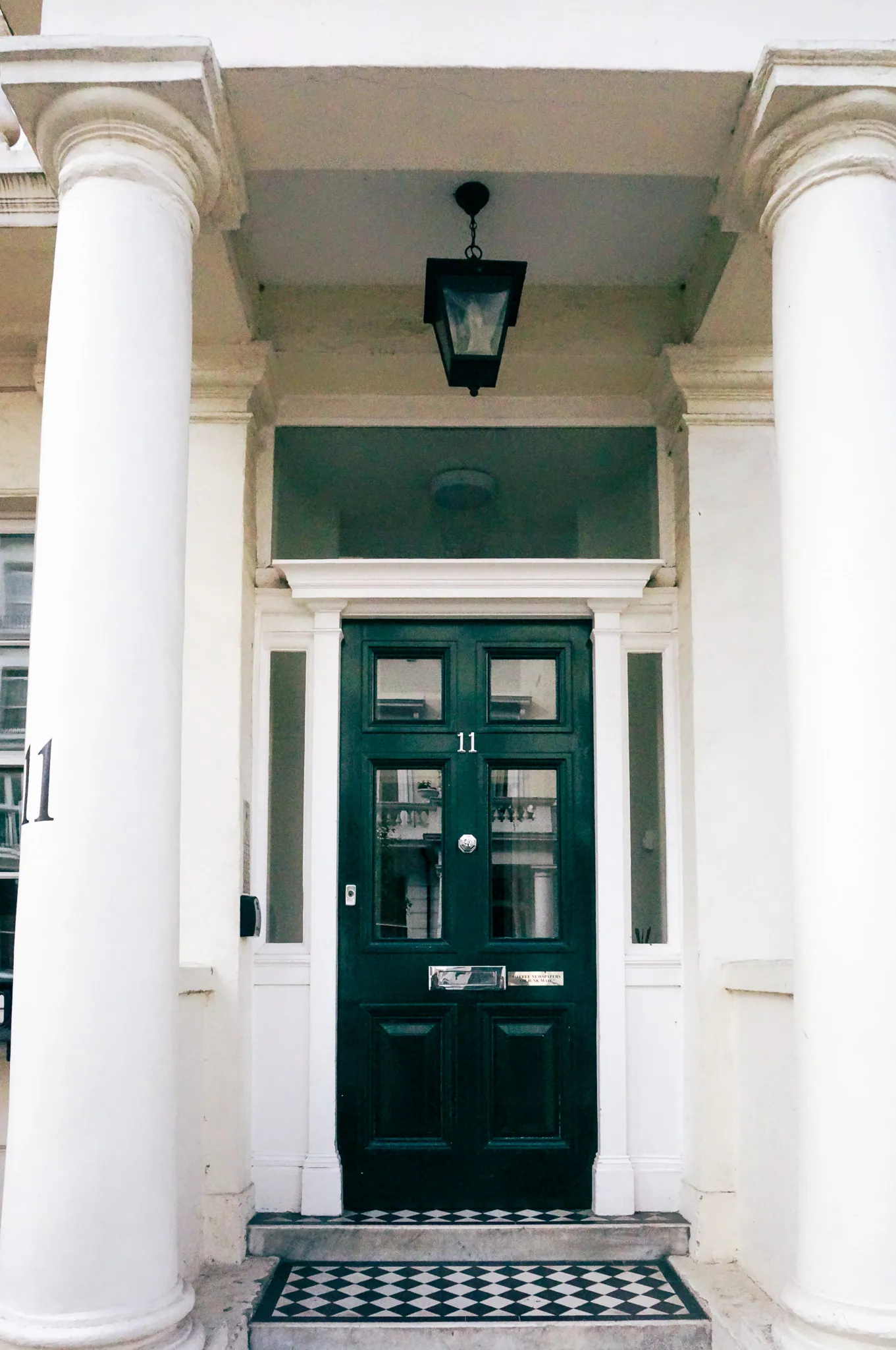 Black front door no. 11 between white columns