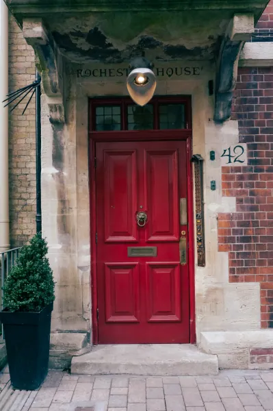 Red front door under a carved hood