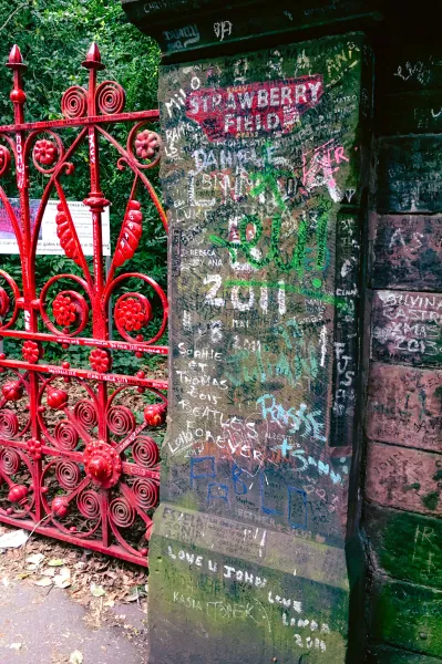 Graffiti-covered gate pillar and red gates