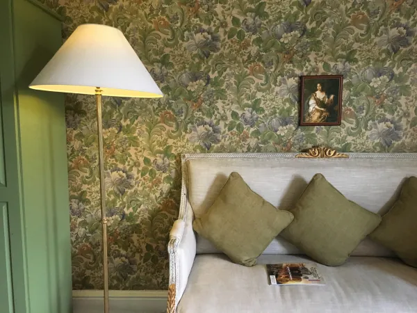 Sofa and lamp against floral wallpaper