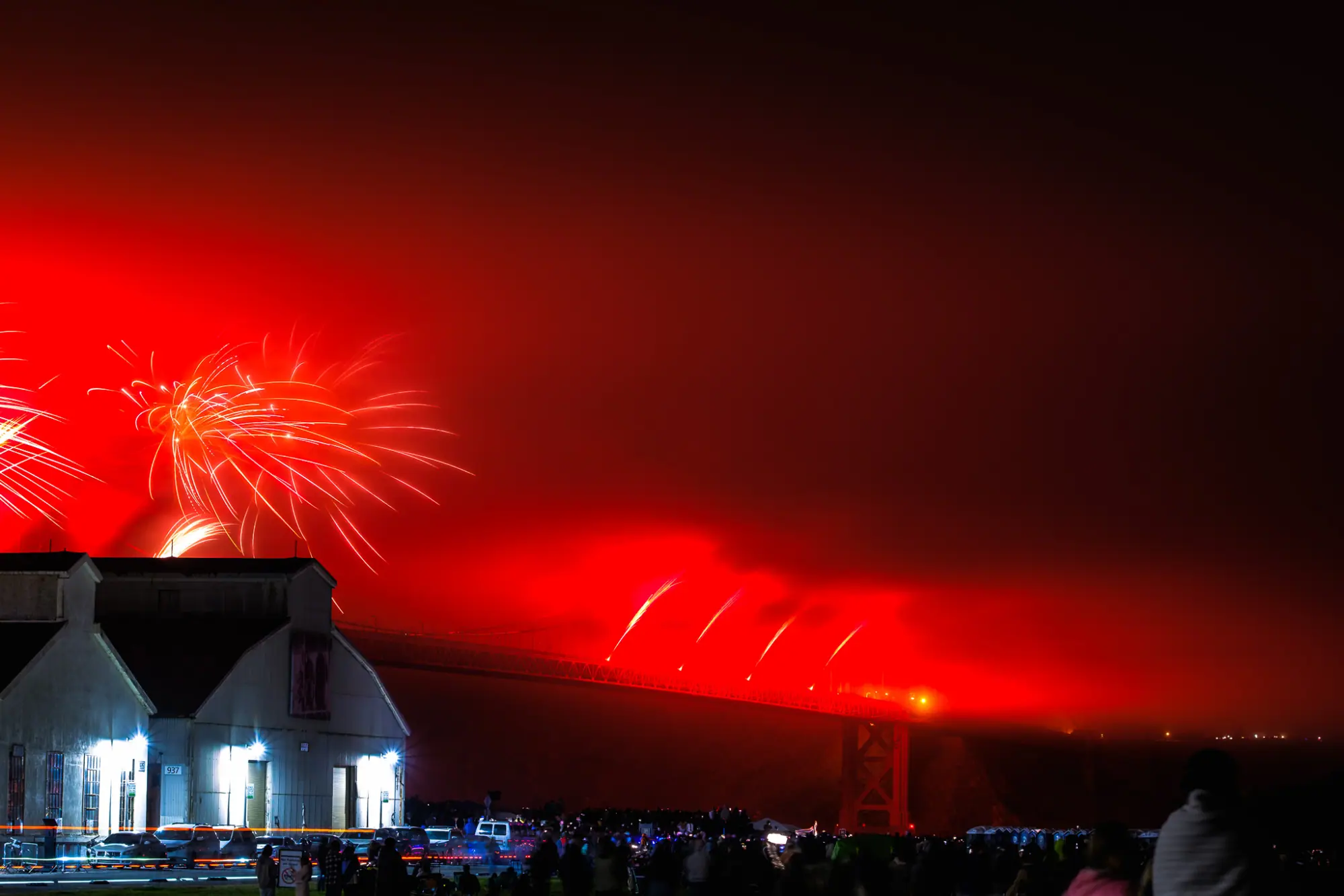 Red bursts lighting the fog over the bridge